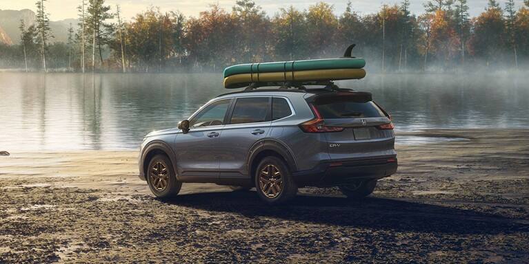2027 Honda CR-V EX in Urban Gray Pearl back parked by a lake with surfboards on the roof (Compact Crossover SUV).