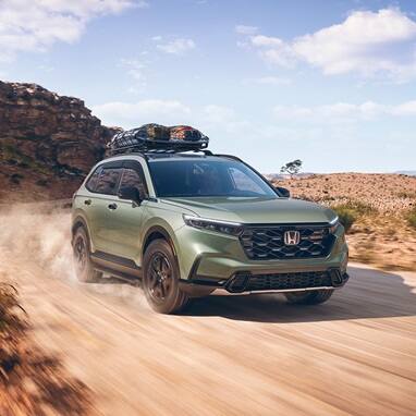2027 Honda CR-V TrailSport Hybrid in Ash Green Metallic front driving on a desert road (Compact Crossover SUV).