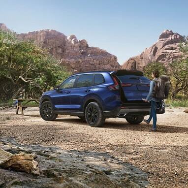 2027 Honda CR-V Sport Touring Hybrid in Canyon River Blue Metallic parked in a mountain landscape (Compact Crossover SUV).